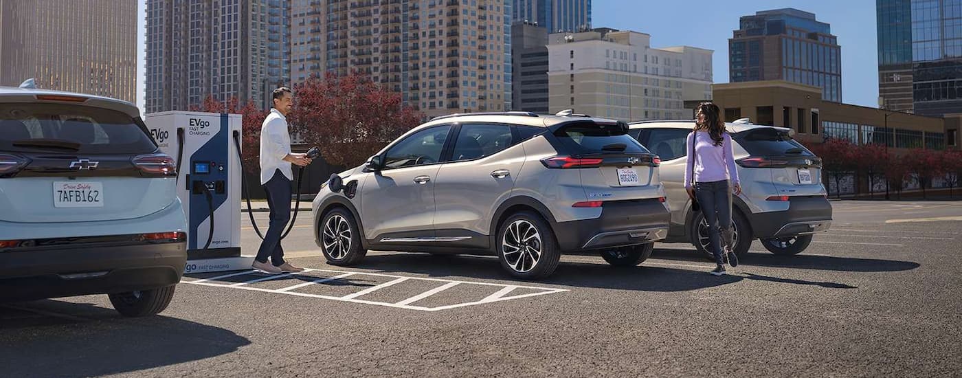 A silver 2023 Chevy Bolt EUV is shown charging at and EVgo station.