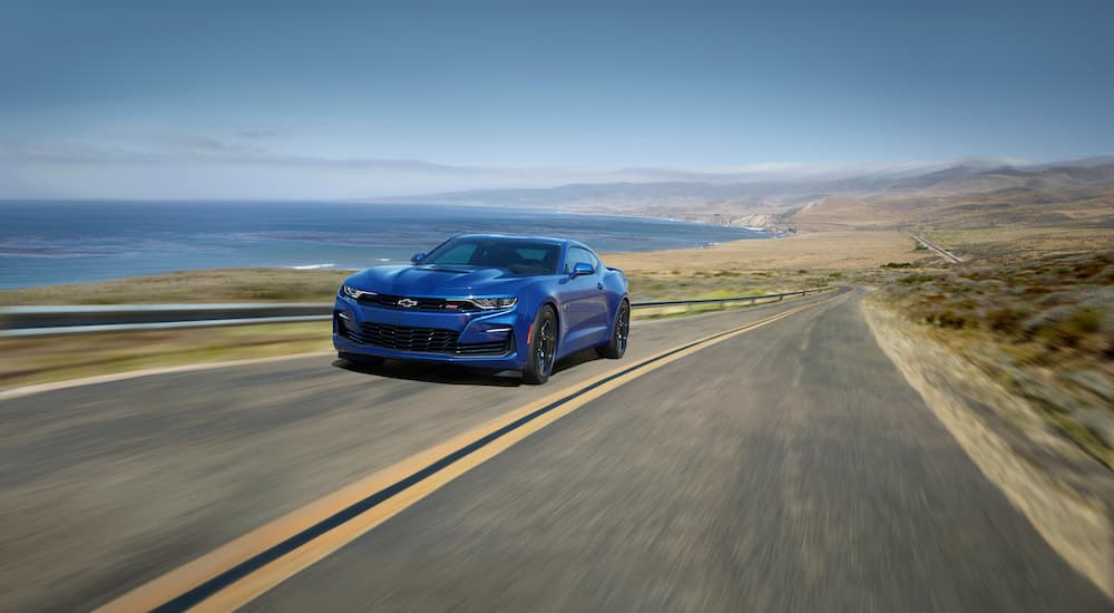 A blue 2021 Chevy Camaro SS is shown driving on a coastal road.