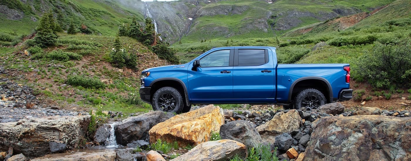 A blue 2022 Chevy Silverado 1500 ZR2 parked on a rocky trail in the mountains.