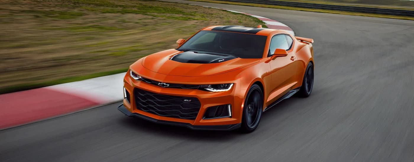 An orange 2022 Chevy Camaro ZL1 driving on a racetrack.