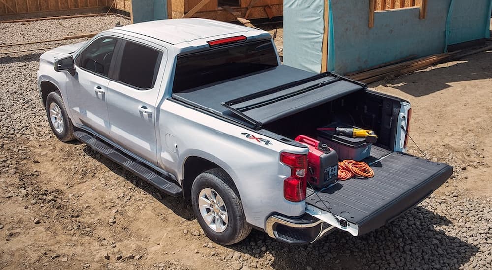 A silver 2022 Chevy Silverado LTD is shown parked at a construction site with tools in the bed.