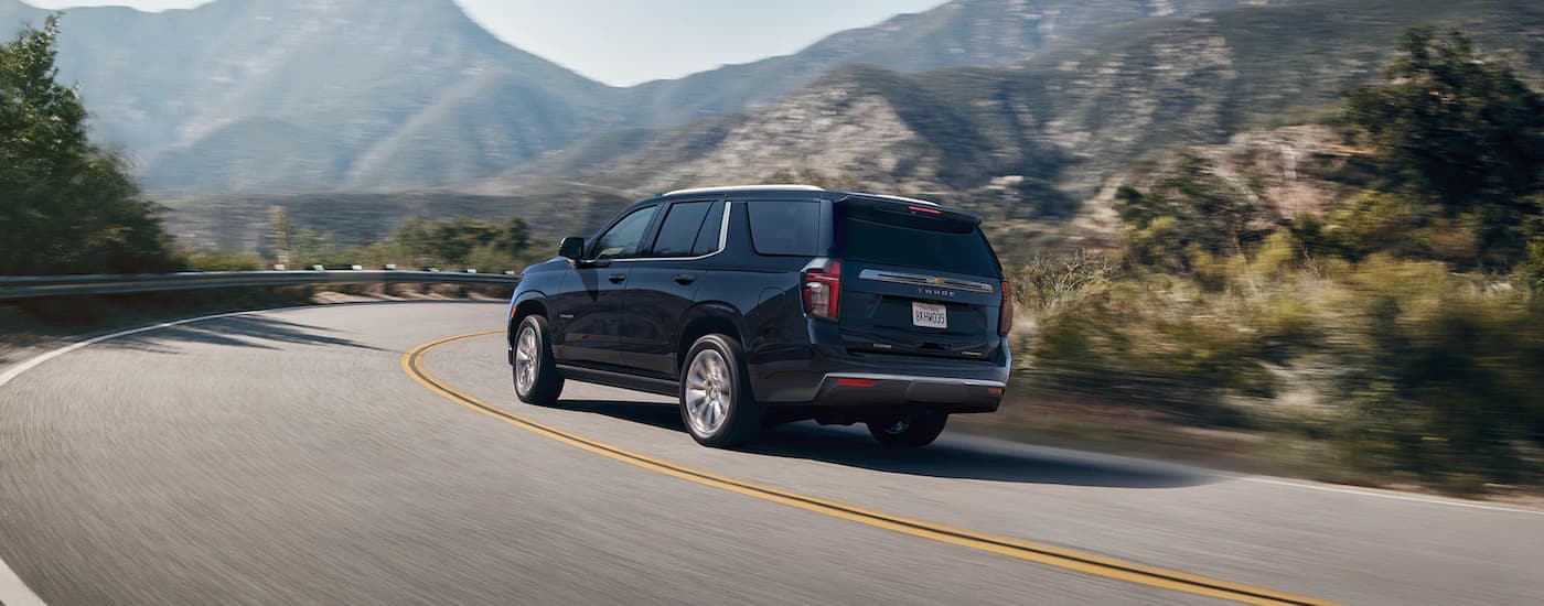 A dark blue 2022 Chevy Tahoe driving on a winding mountain road.