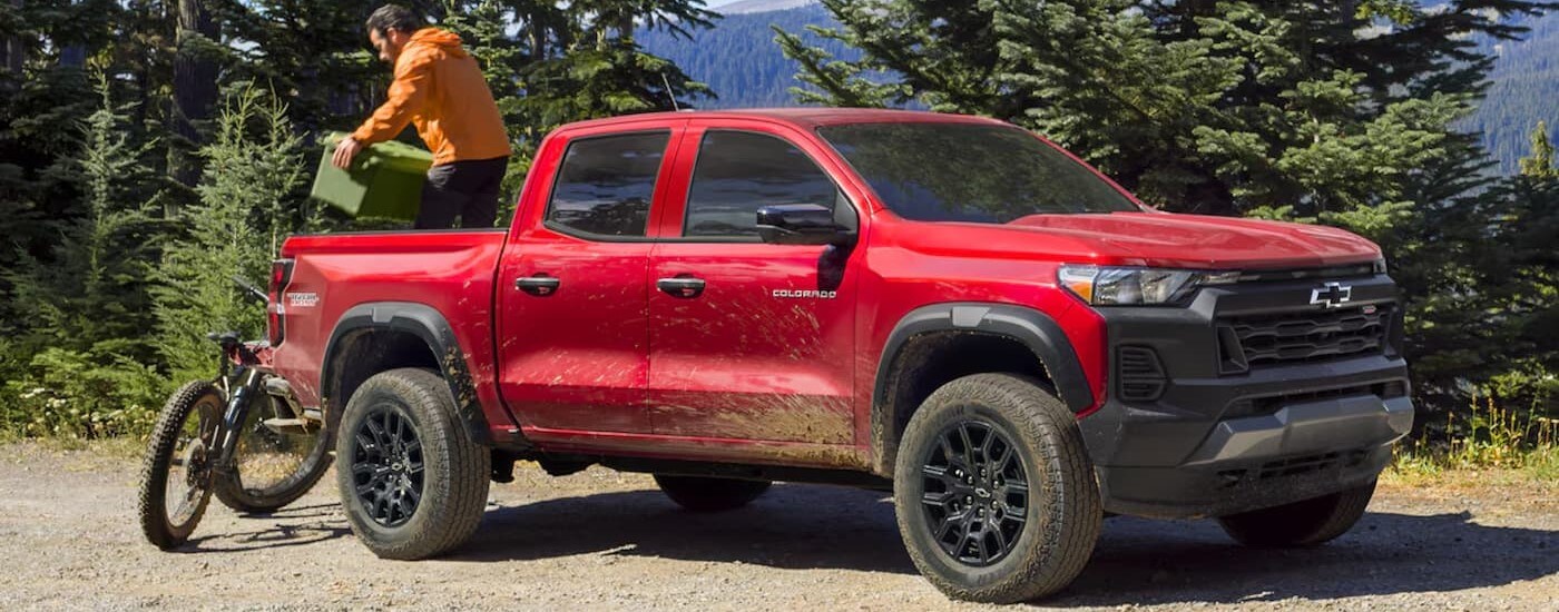 A red 2024 Chevy Colorado Trail Boss is shown parked off-road after viewing work trucks for sale.