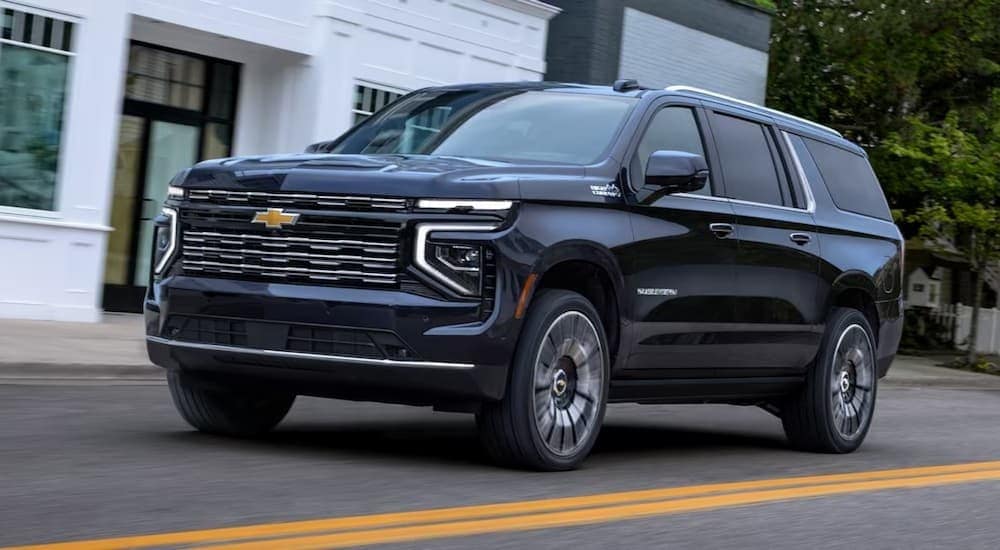  A blue 2025 Chevy Suburban High Country is shown driving on a city street.