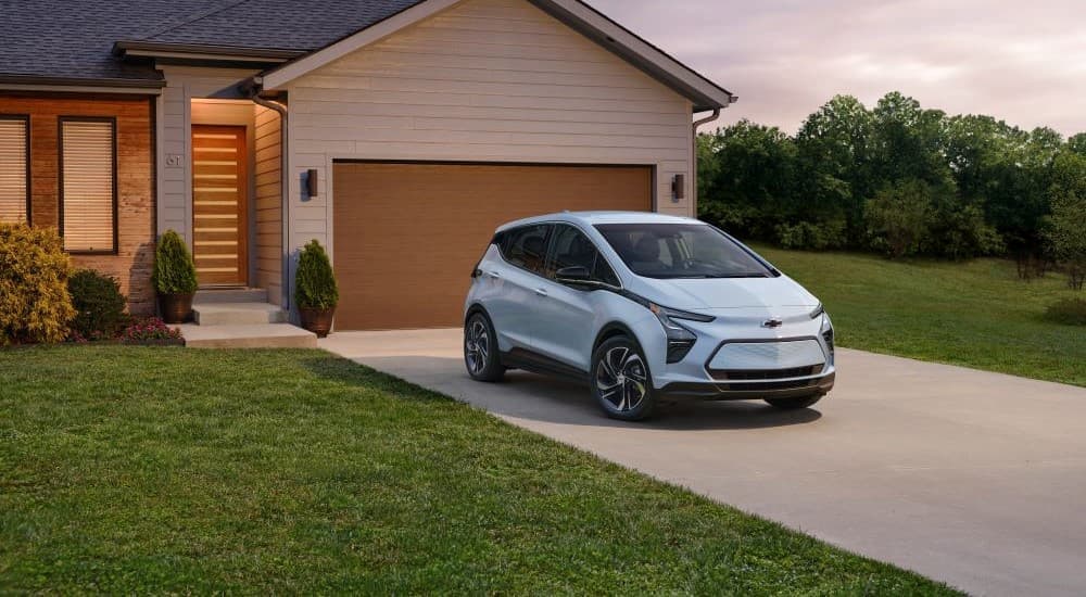 A blue 2023 Chevy Bolt EV is shown parked on a driveway.