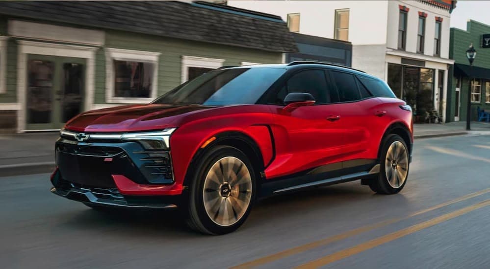 A red 2025 Chevy Blazer EV RS is shown driving to a Chevy dealer near Woodland.