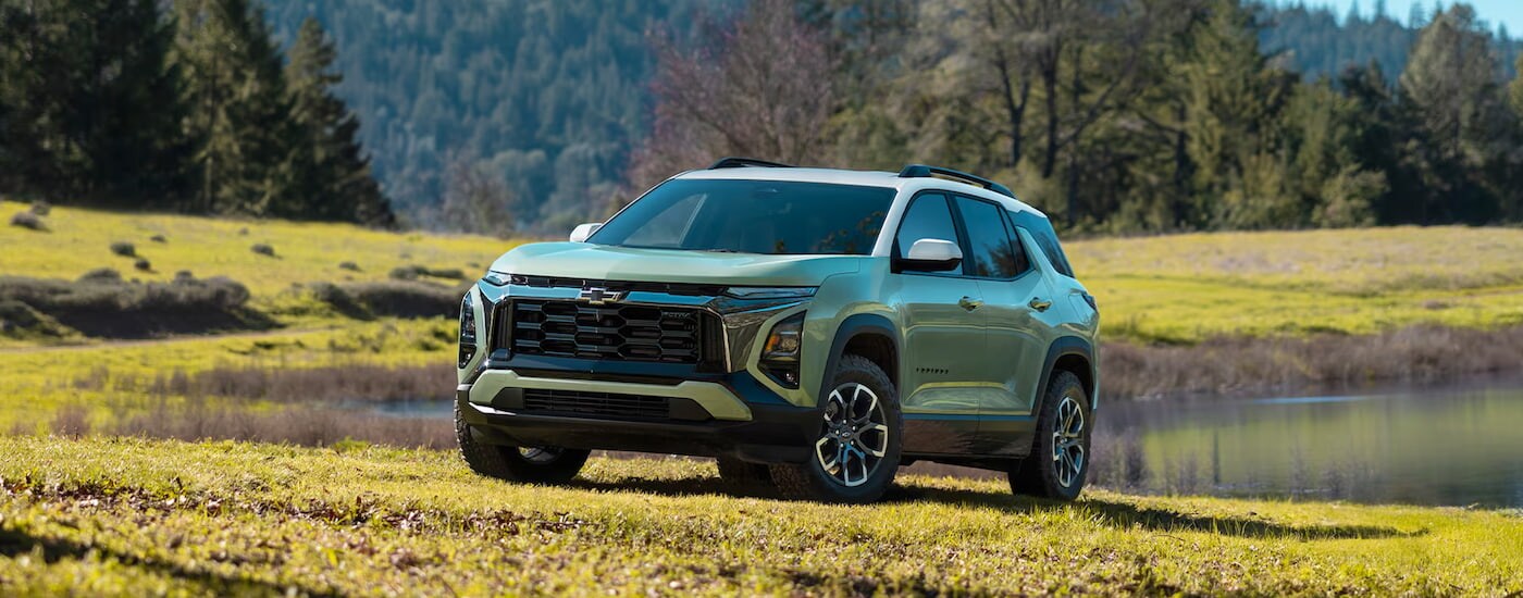 A green 2025 Chevy Equinox ACTIV parked at a pond near a Chevy dealer.
