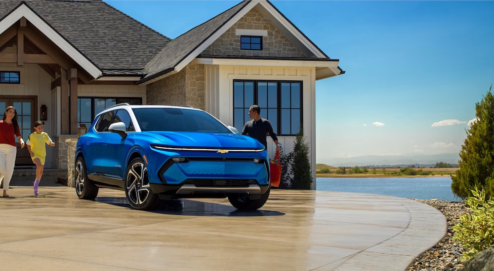 A blue 2024 Chevy Equinox EV parked outside a family home.