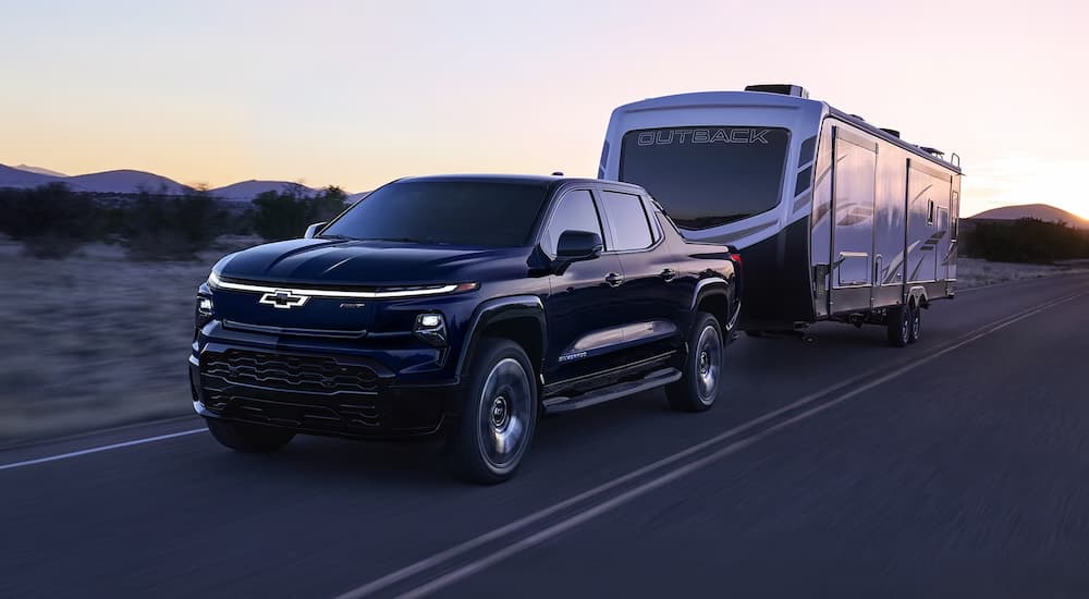 A black 2024 Chevy Silverado RST EV towing an RV to a Chevy dealer near Arden-Arcade.