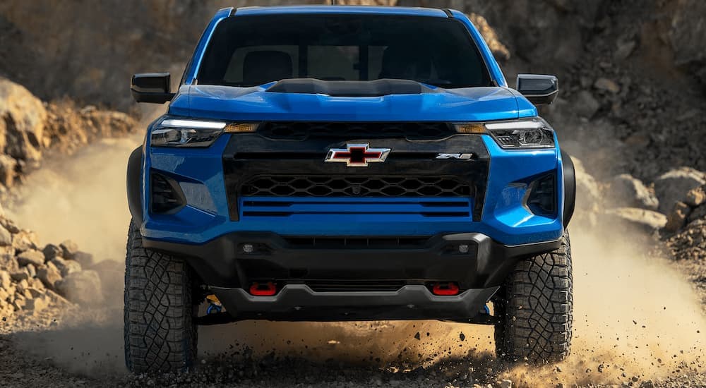 A blue 2025 Chevy Colorado ZR2 driving on a dusty and sandy trail.