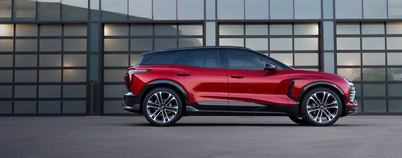 Side view of a red 2024 Chevy Blazer EV SS parked outside a mirrored garage.