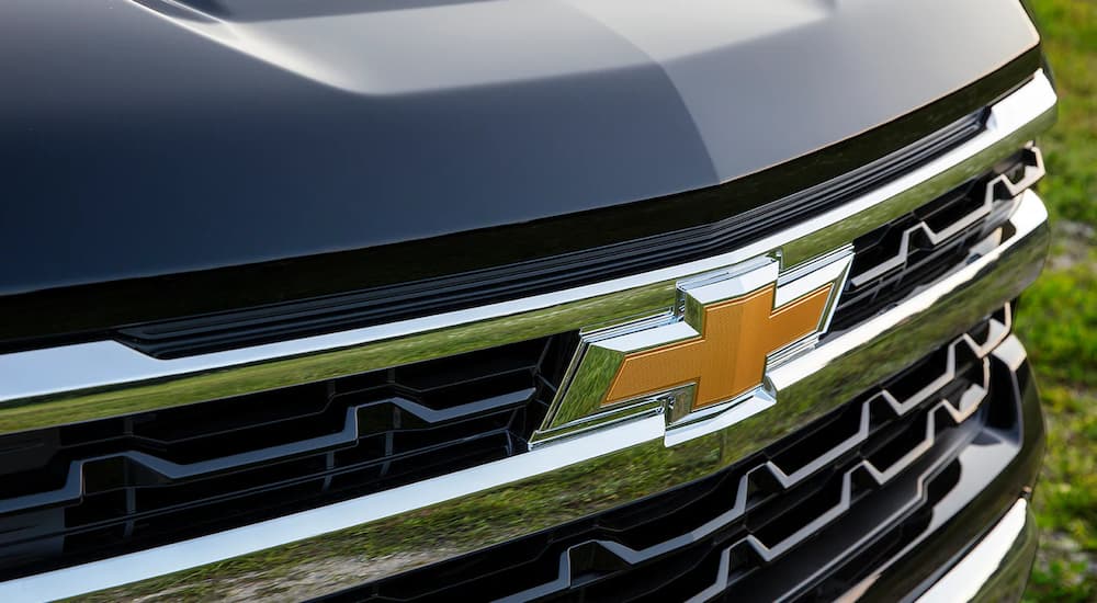 A close up shows the Chevy bowtie logo on the grille of a dark blue 2022 Chevy Silverado 1500.