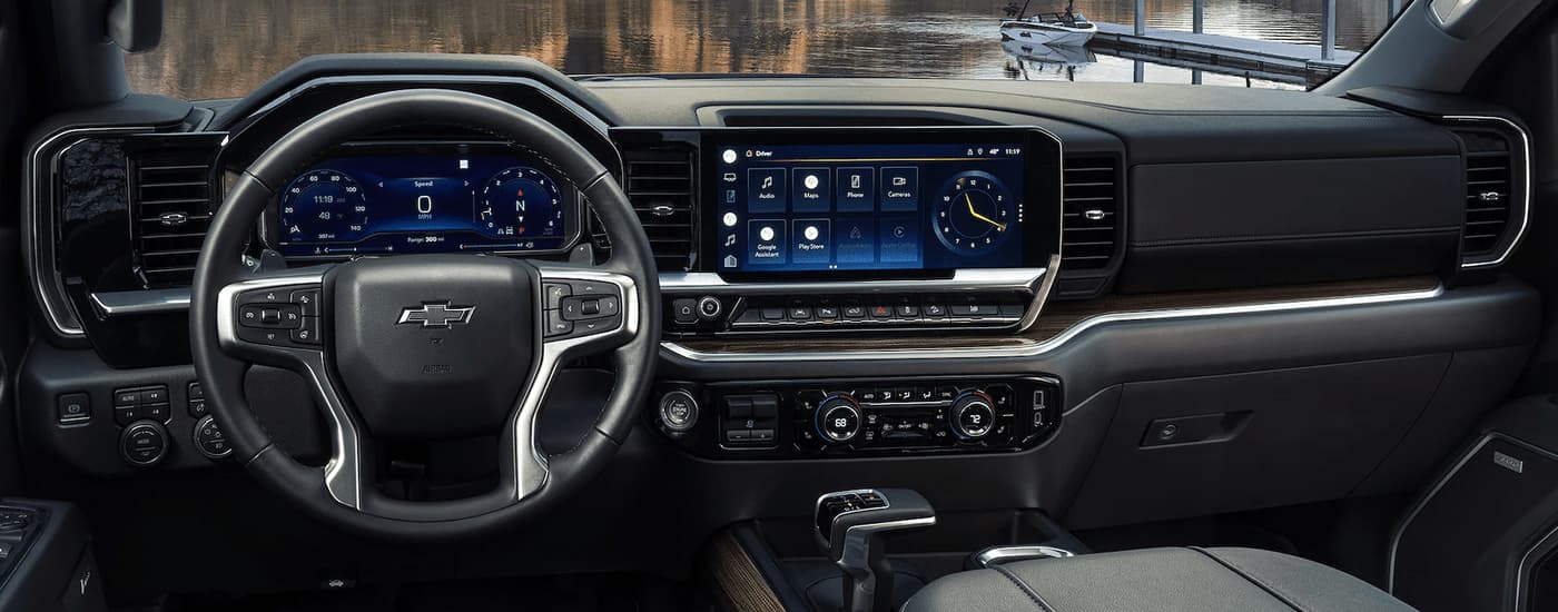 The black and silver interior of a 2023 Chevy Silverado 1500 shows the steering wheel and center console.