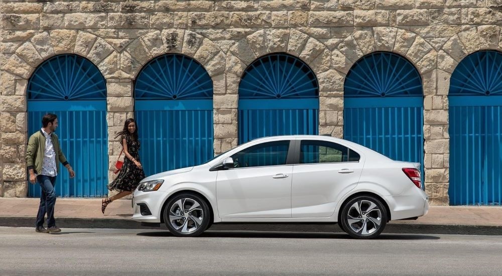 A white 2020 Chevy Sonic LT is shown from the side parked on a city street.
