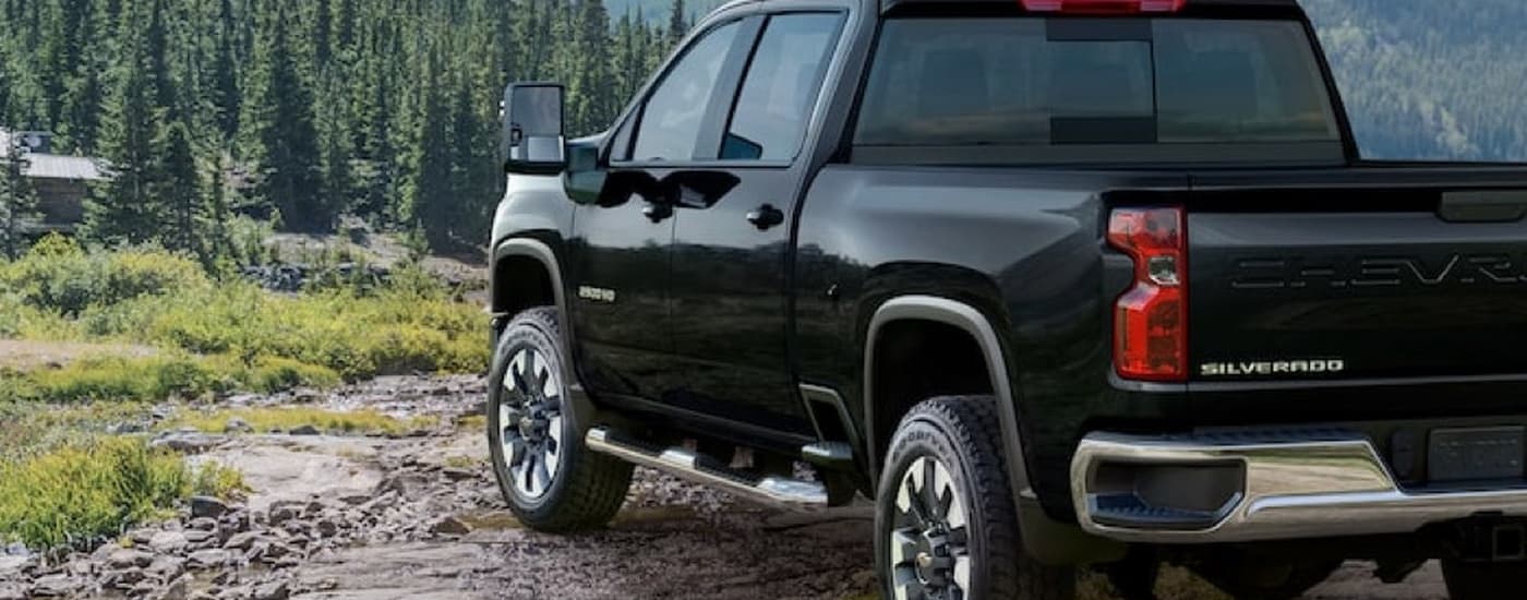 A black 2022 Chevy Silverado 2500HD driving through mountain woods.