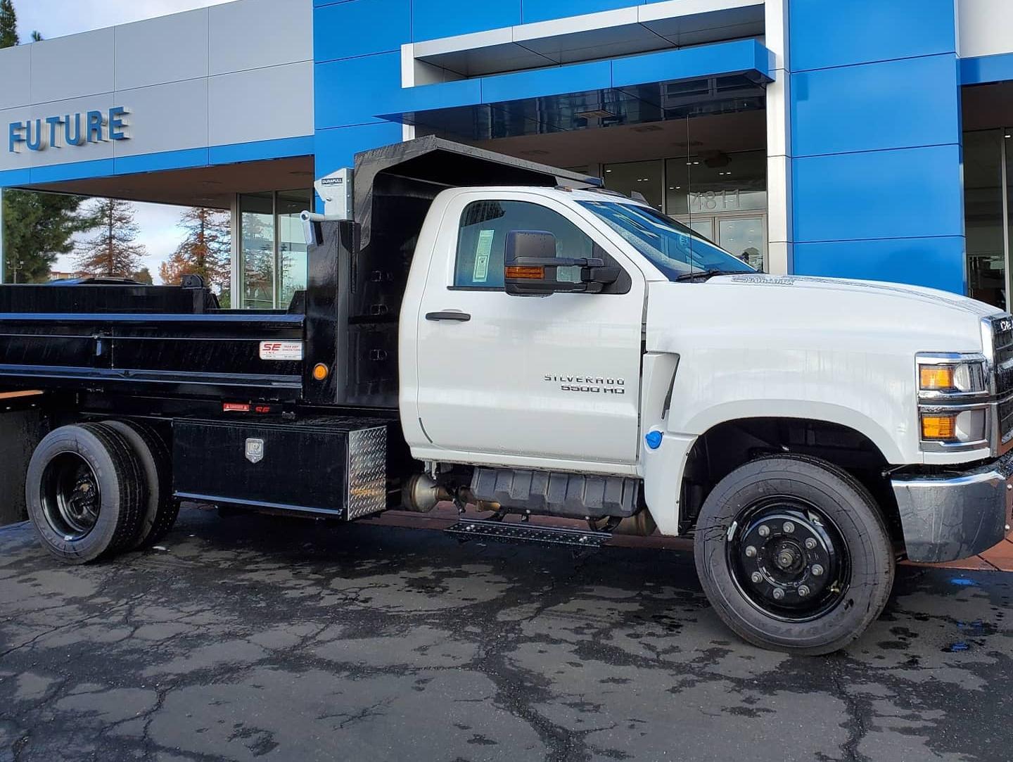 White Chevy Silverado 5500HD with Scelzi Dump Truck body, seen from the side in front of the Future Chevrolet Dealership