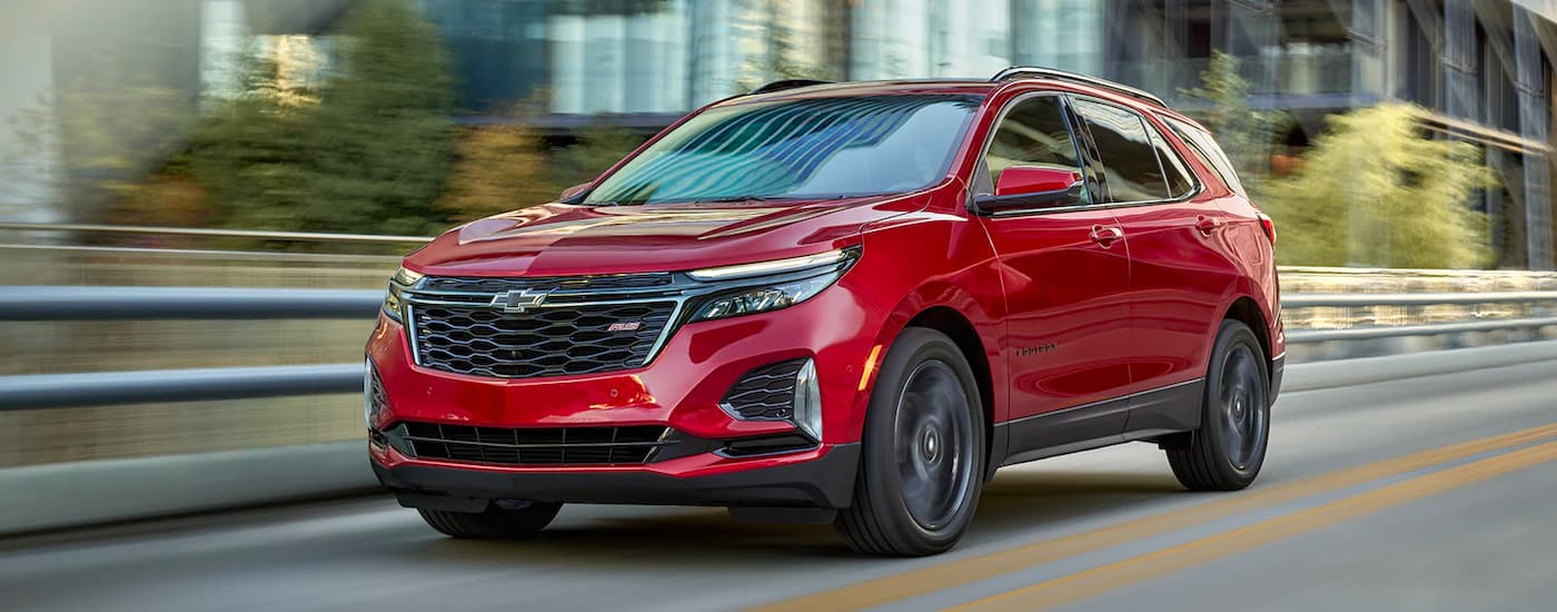 A red 2022 Chevy Equinox RS is shown driving down a blurred city street.
