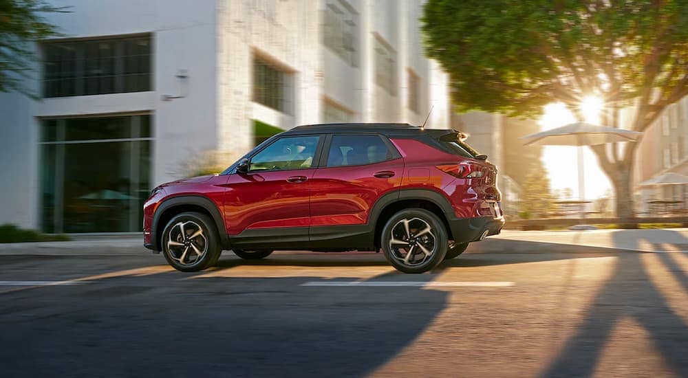 A red 2022 Chevy Trailblazer RS driving past city buildings and trees in the afternoon light