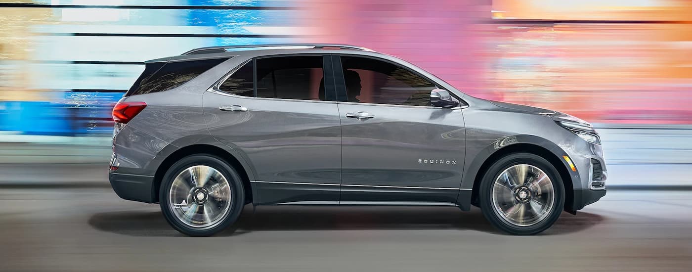 A grey 2023 Chevy Equinox LT is shown from the side past a blurred background.
