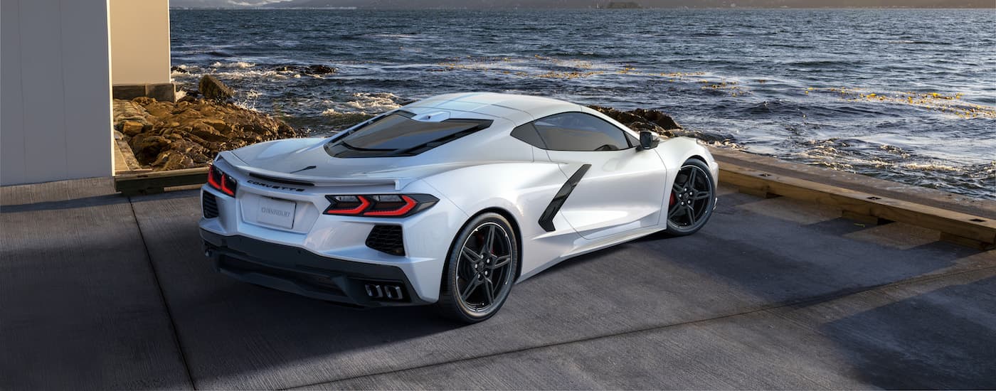 A white 2022 Chevy Corvette parked next to a modern house overlooking the ocean.