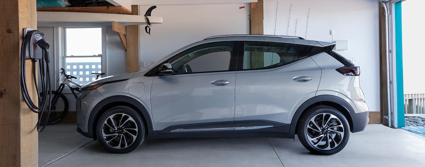 A silver 2023 Chevy Bolt EUV parked next to a home charging station in a garage