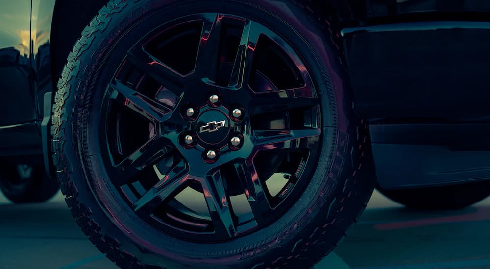 A close up of a shiny black rim on a 2022 Chevy Silverado 1500