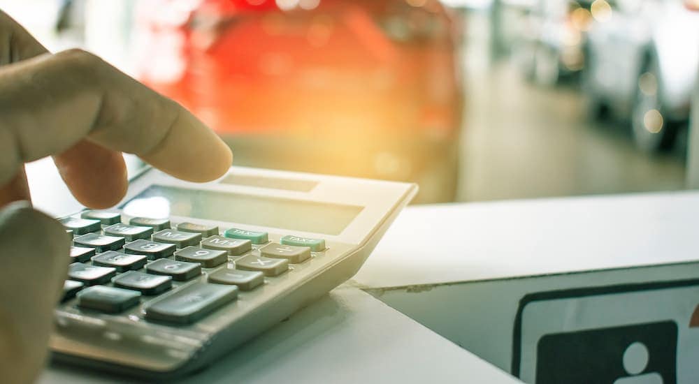 Close-up of someone using a calculator at a car dealership