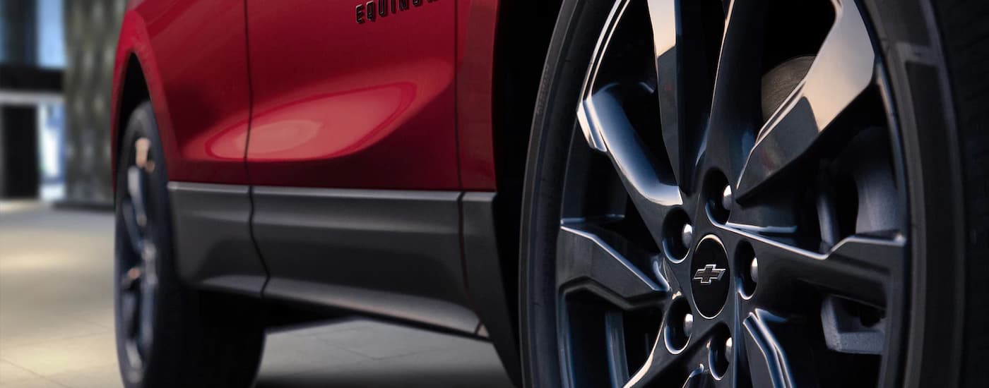 A close up of the side and rims of a red 2023 Chevy Equinox RS.