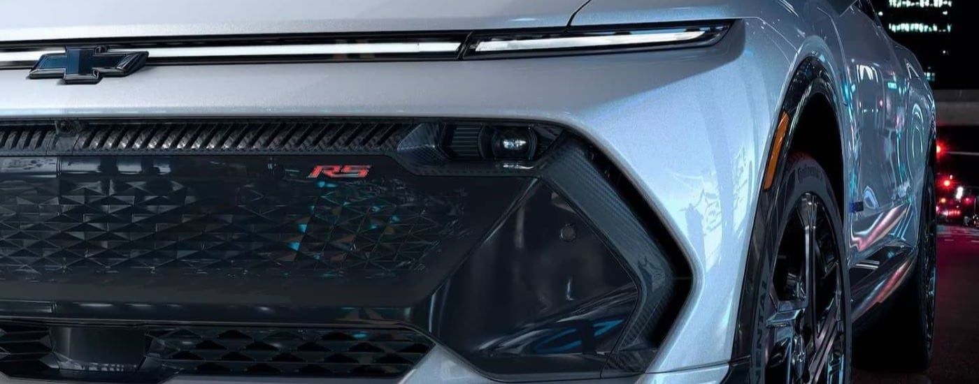 A close up shows the grille and driver side headlight on a white 2024 Chevy Equinox EV RS.