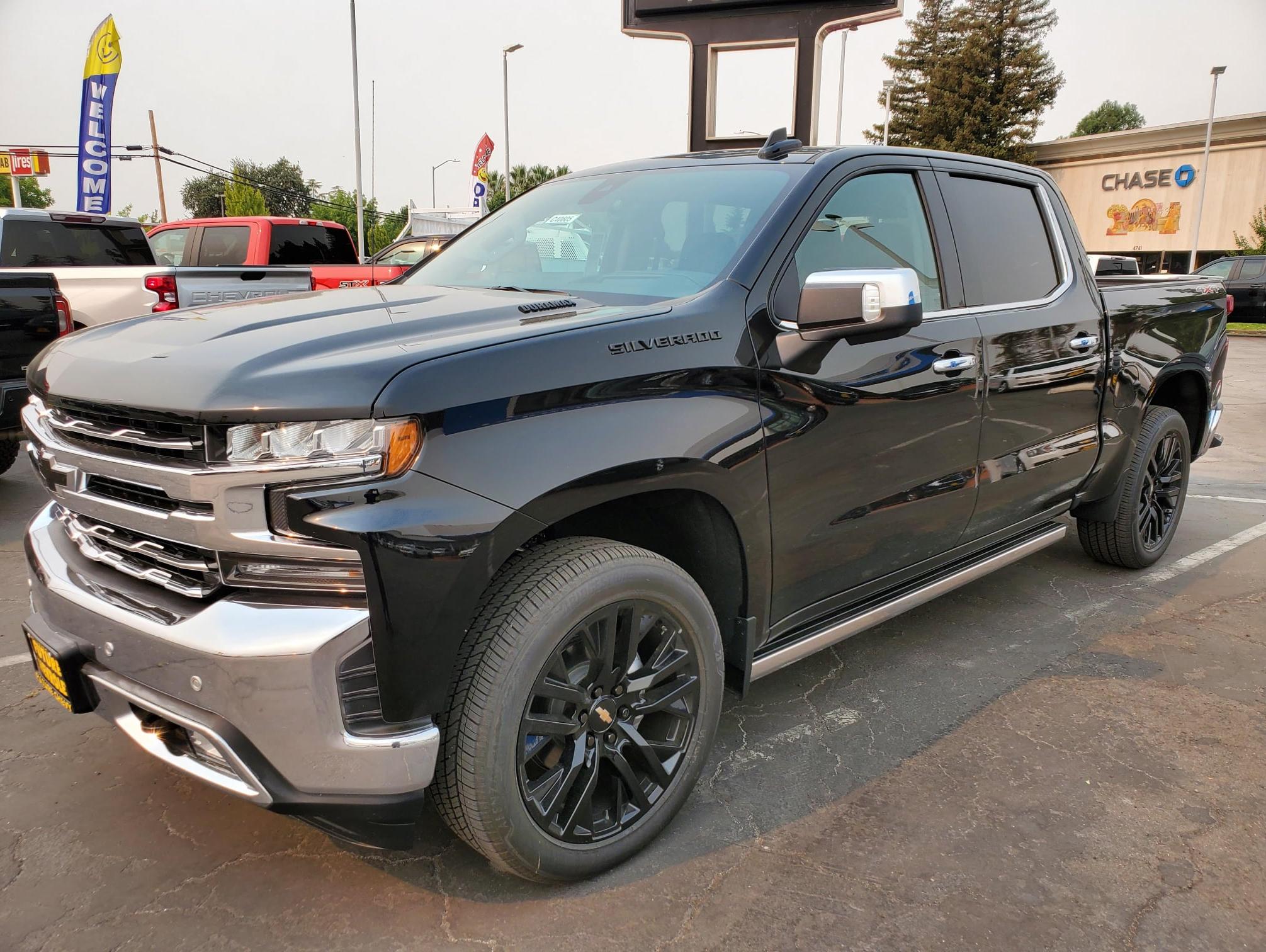 Front angled view of a black Chevy Silverado 1500 LTZ crew cab diesel truck with custom 22 inch wheels