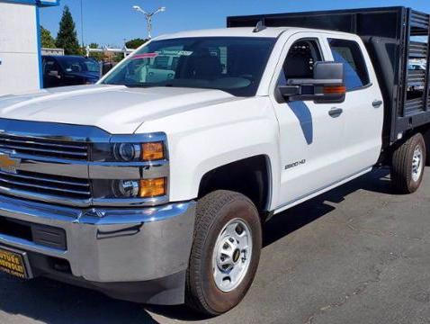 Front view of a white Chevy Silverado 2500HD crew cab with 8 foot stake bed
