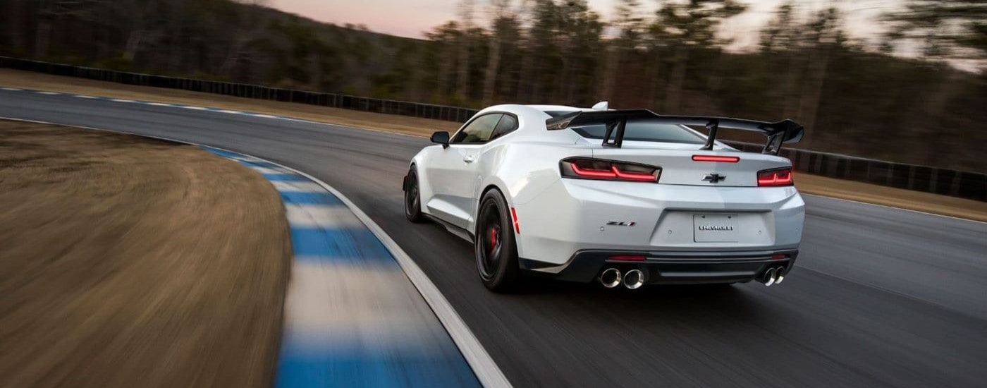 A white 2024 Chevy Camaro ZL1 is shown from the rear on a racetrack.