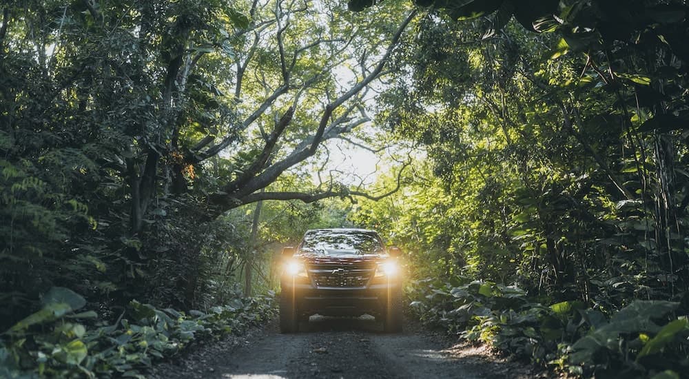 A red 2022 Chevy Colorado ZR2 is shown from the front driving on a path in the woods.