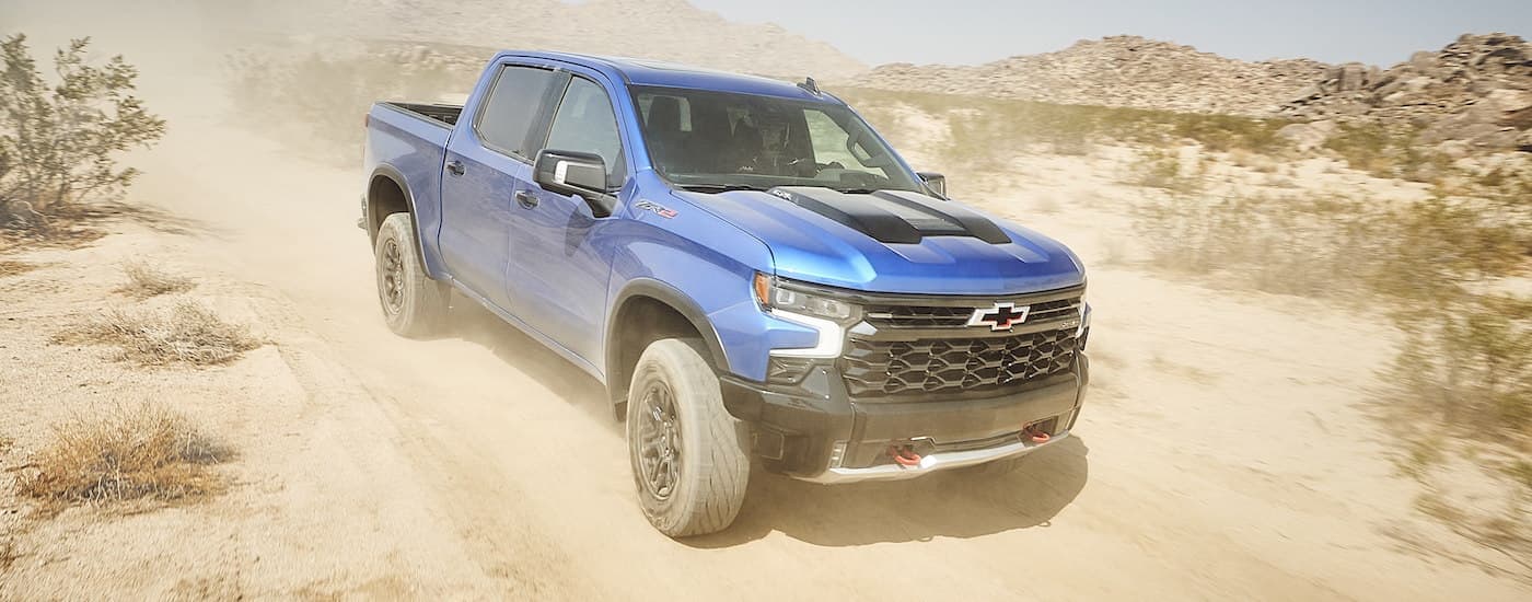 A blue 2022 Chevy Silverado 1500 ZR2 kicking up dust on a desert trail after visiting a California Chevrolet dealer.