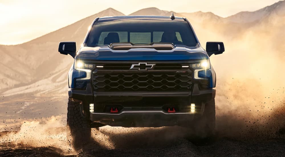A blue 2023 Chevy Silverado 1500 ZR2 driving towards the camera on a dusty trail.
