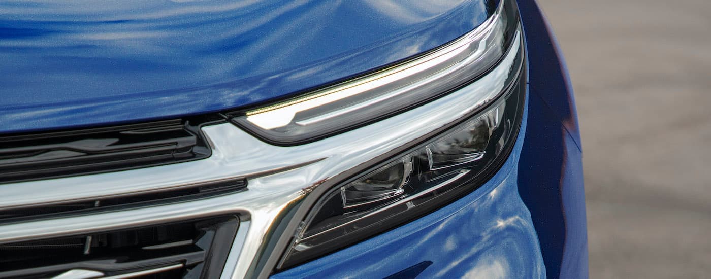 The driver side headlight is shown on a blue 2023 Chevy Equinox LT.