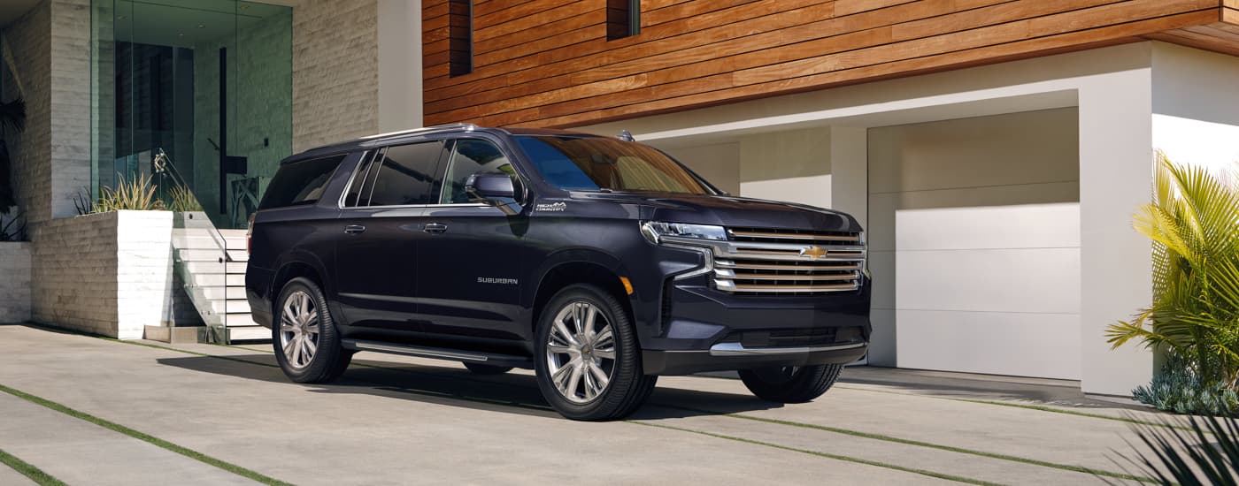 A dark blue 2023 Chevy Suburban High Country is shown parked in a driveway.