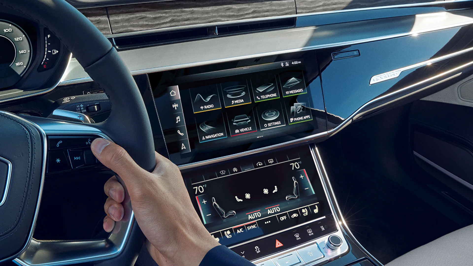 Vue intérieure de l’Audi A8 2025 montrant l’écran tactile double du système MMI, le volant multifonction et les commandes de climatisation.