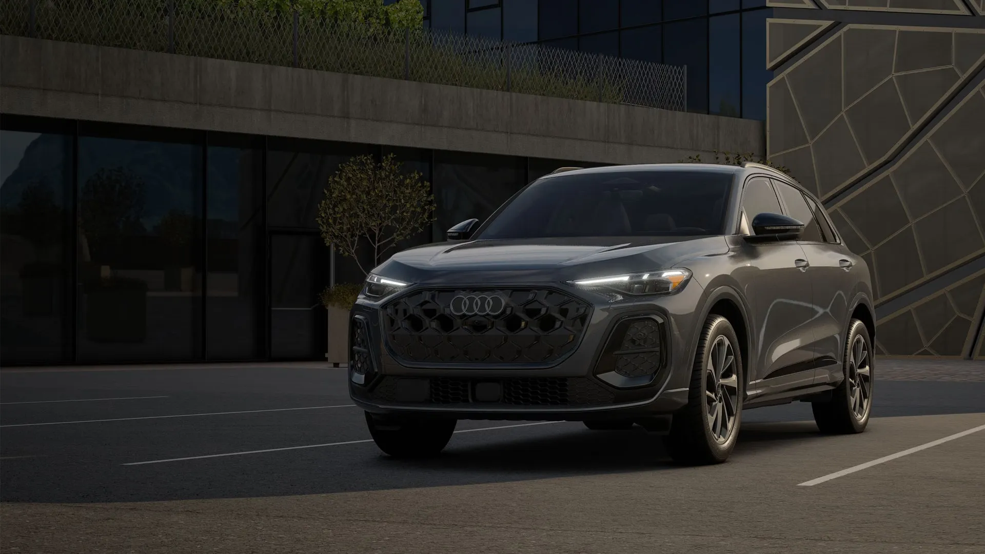 2025 Audi Q5 in grey, three-quarter front view, parked in a modern lot with geometric walls and greenery.