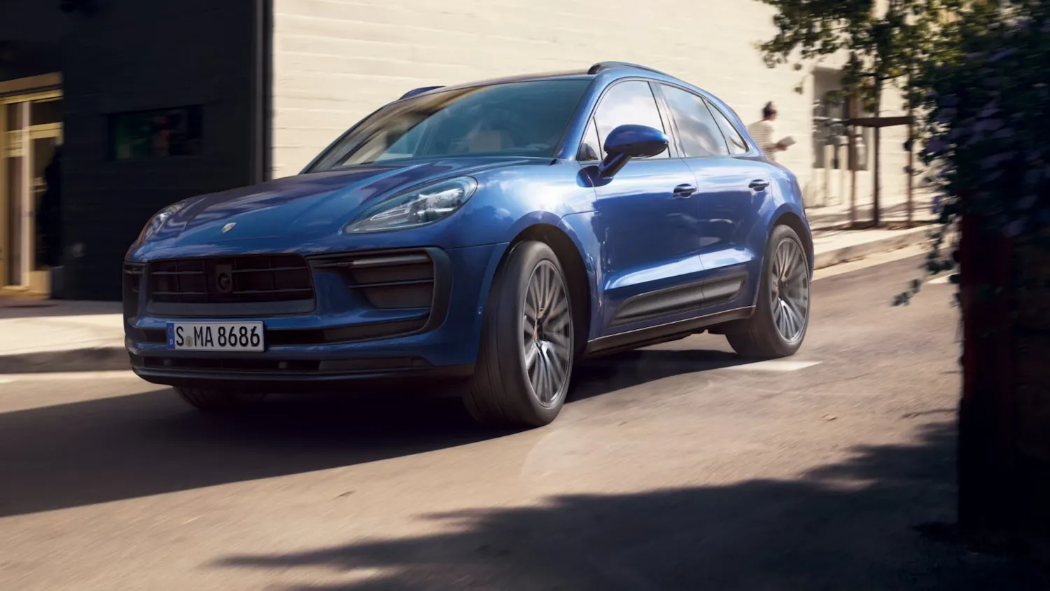 2025 Porsche Macan blue three-quarter front left view driving on an urban road.