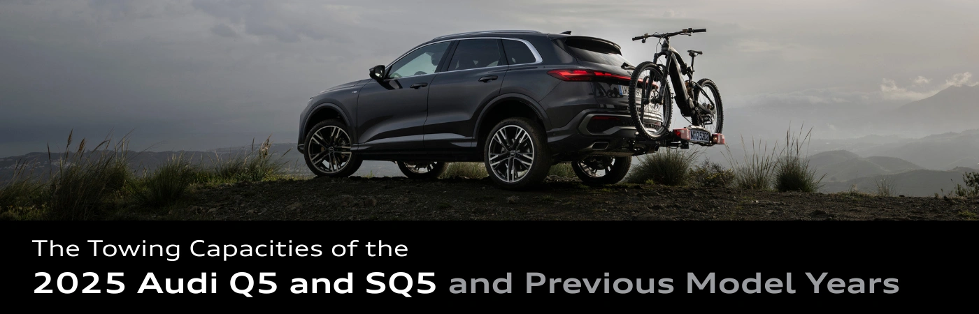 2025 Audi Q5 in gray with a bike rack attached, parked high up in front of a misty mountain landscape.