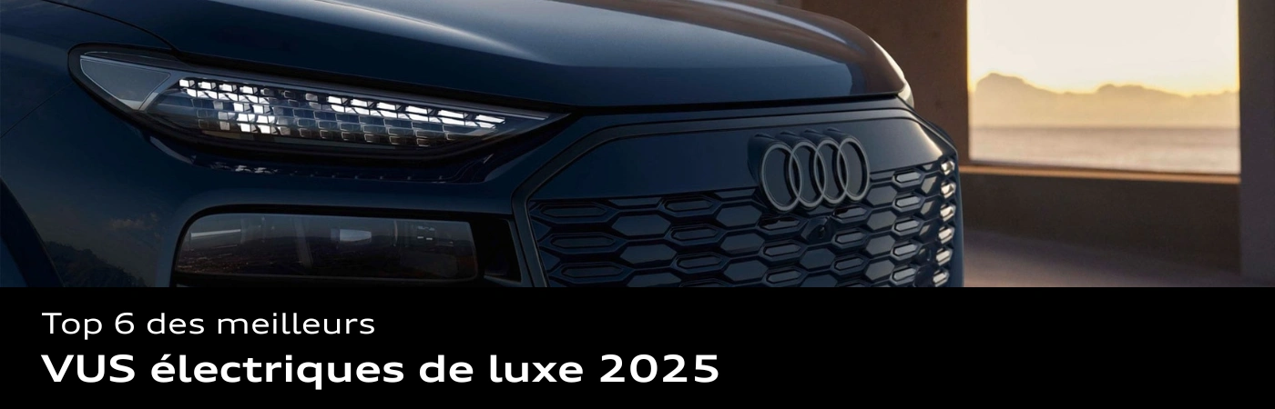 Gros plan sur la calandre et le phare gauche d’un VUS Audi électrique 2025, avec logo Audi bien visible et coucher de soleil en arrière-plan.