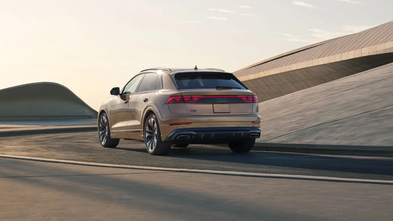 Vue 3/4 arrière du Audi Q8 2025 roulant sur une route.