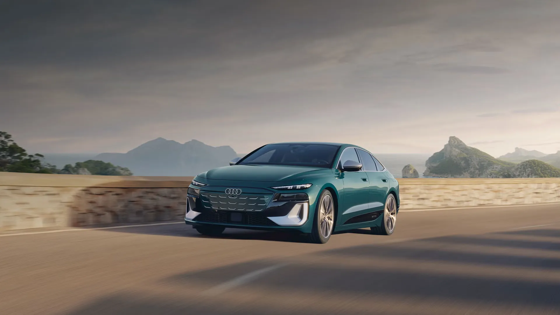 2025 green Audi S6 e-tron driving on a coastal road, three-quarter front view with sea and mountains in the background.