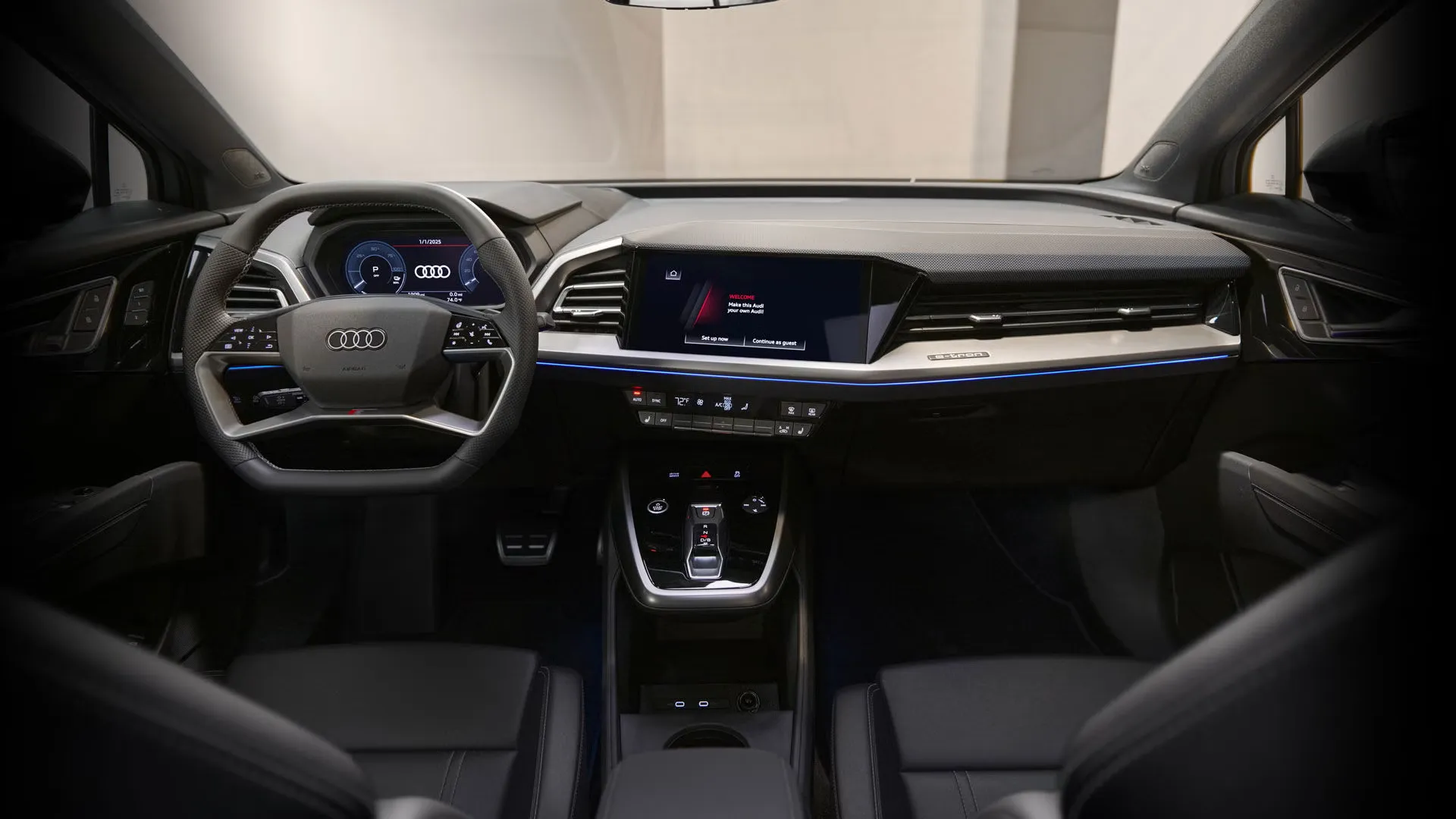 Interior view of the 2025 Audi Q4 Sportback e-tron showing illuminated digital dashboard and central screen, sport steering wheel in the foreground.