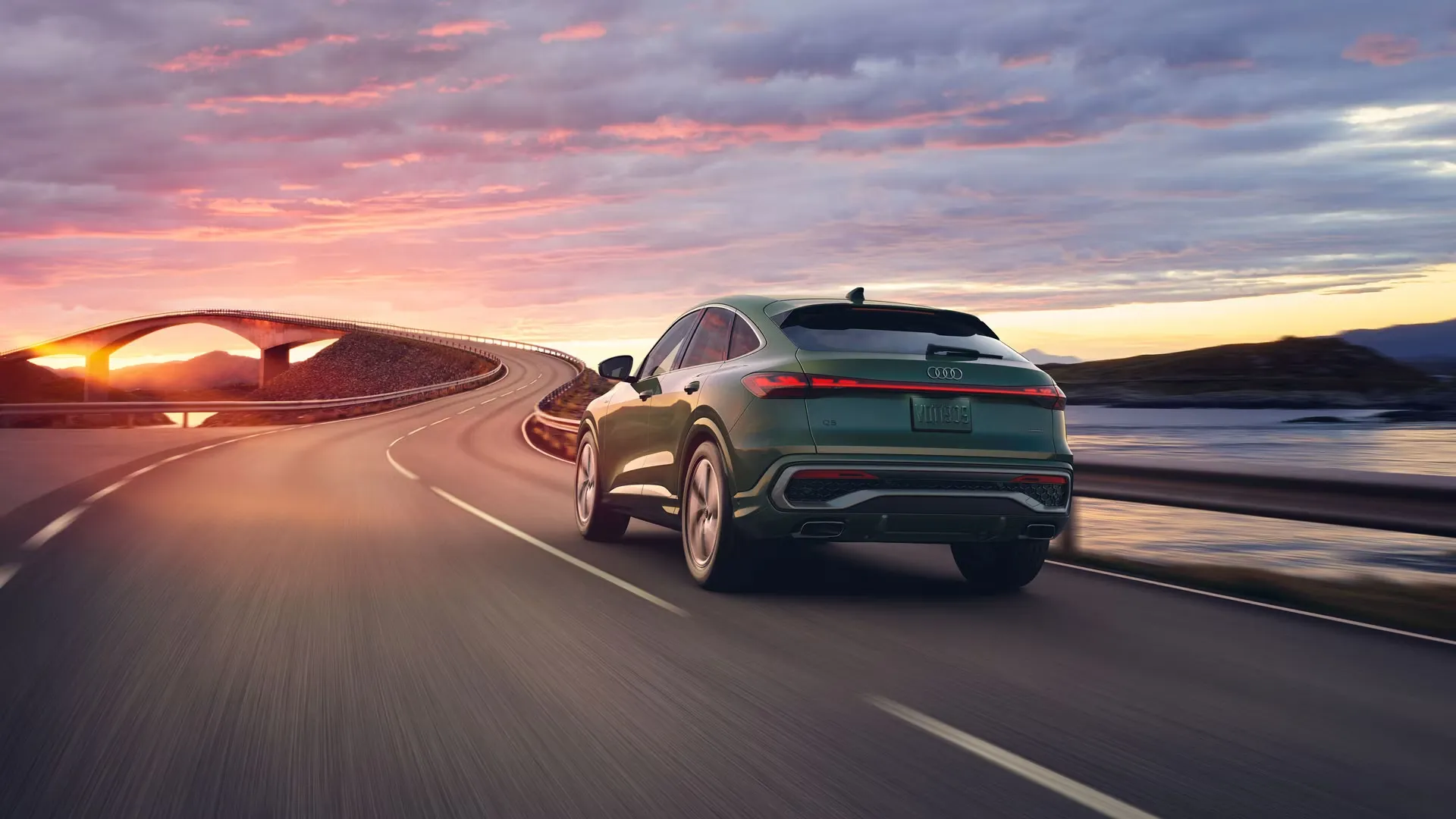 Vue 3/4 arrière du Audi Q5 Sportback 2025 roulant sur une route.