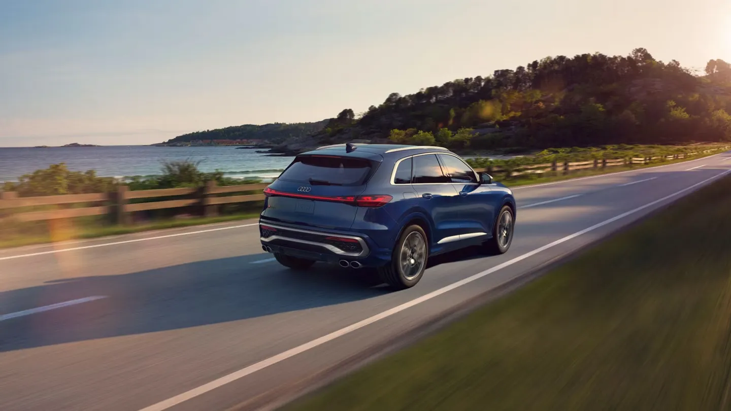 2025 Audi SQ5 blue rear view on a coastal road, emphasizing the sportiness and elegance of this luxury SUV.