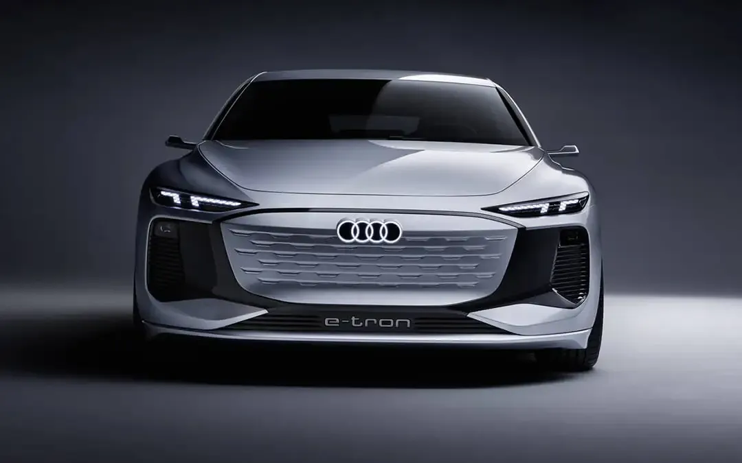 Audi A4 e-tron 2025 argentée vue de face, avec calandre fermée e-tron et phares à DEL effilés sur fond studio sombre.