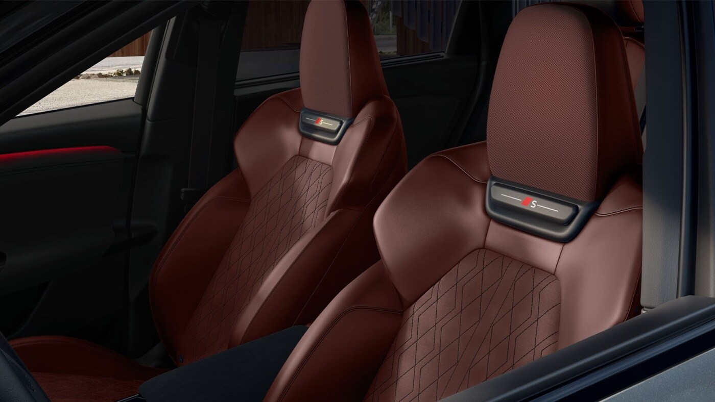Close-up of the 2025 SQ6 e-tron brown sport leather seats with diamond stitching and illuminated S logo on the headrests.