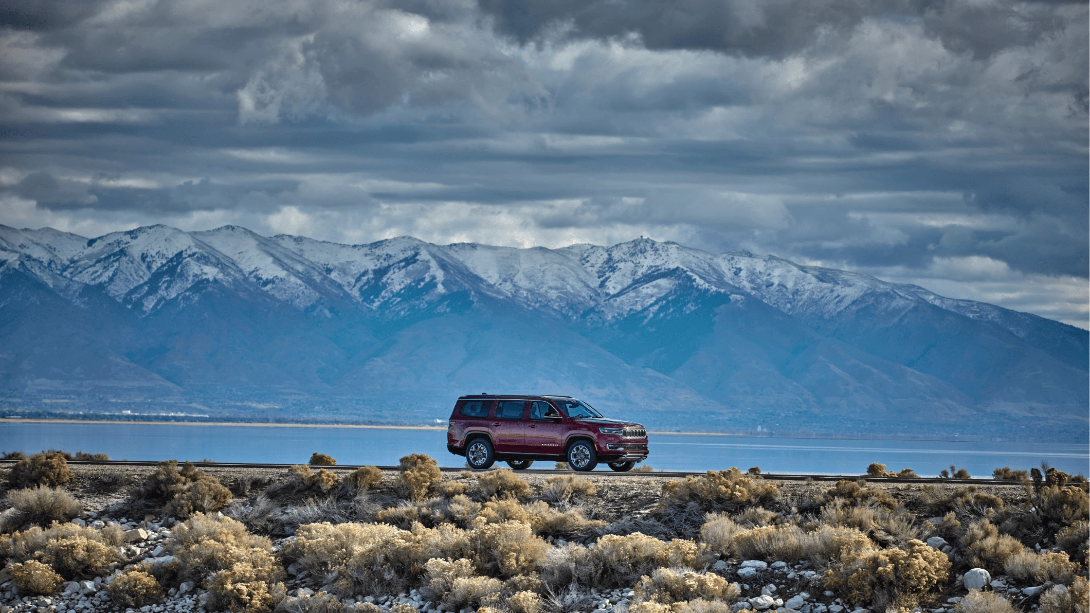 2025 Jeep Wagoneer SUV parked near snowy mountains under a cloudy sky in Fort Myers